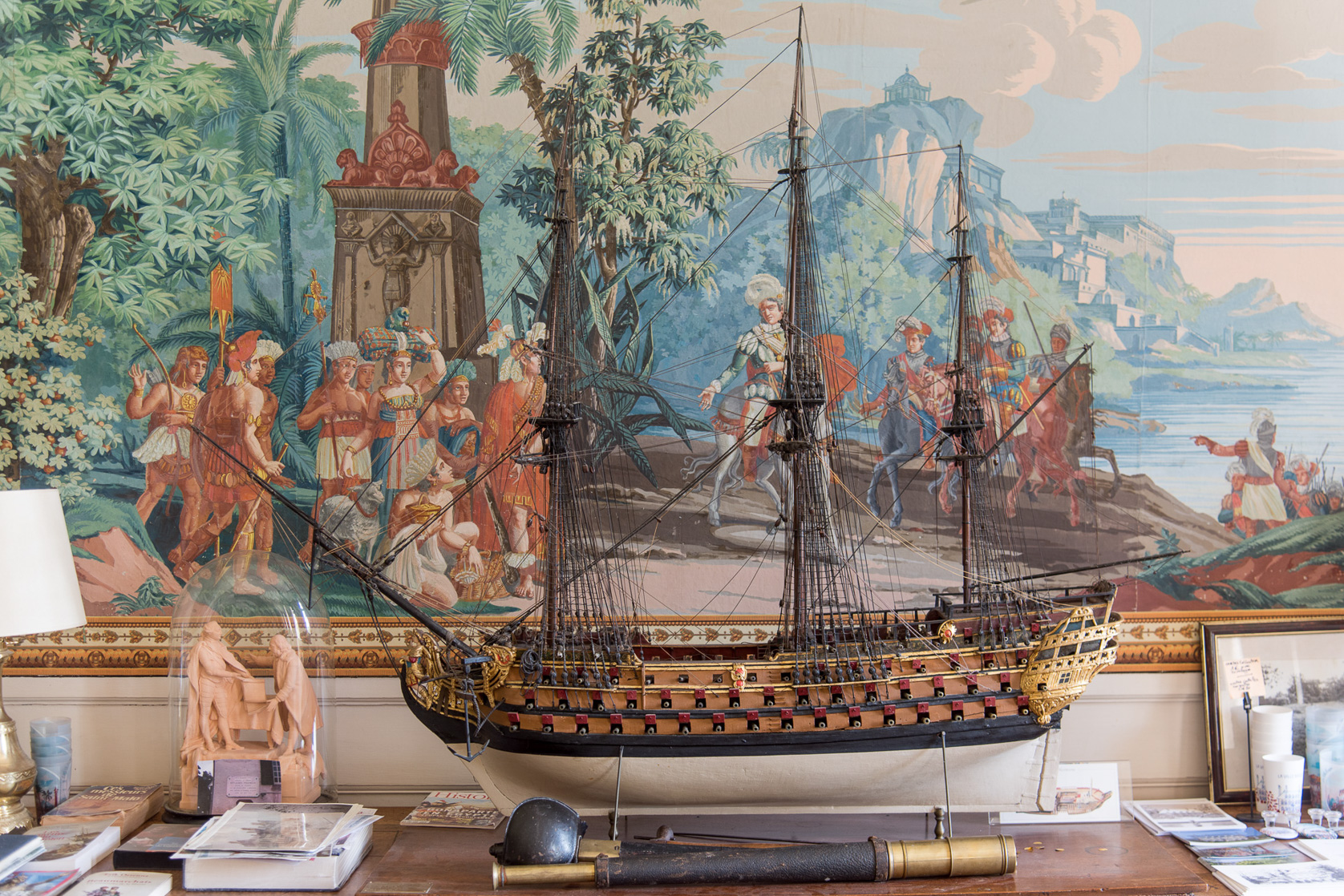 Maquette de bateau devant un détail du papier peint panoramique.