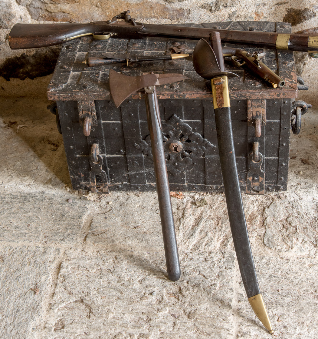 Exposition d'armes d'époque dans le pigeonnier. Un sabre, une hache d'abordage, un tromblon (sorte de fusil), un poignard et un pistolet de corsaire.